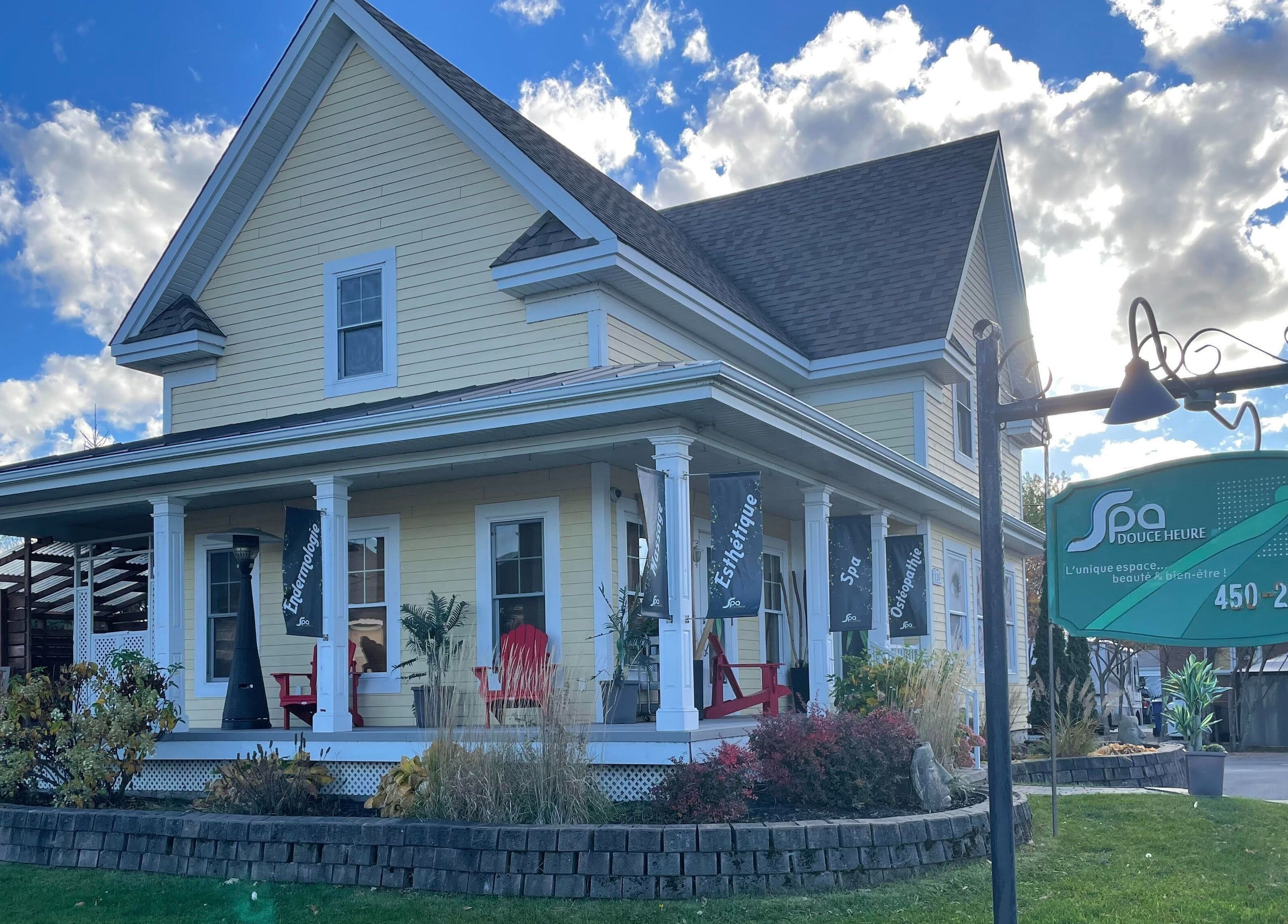 Devanture charmante de Spa Douce Heure à Les Coteaux, Québec, CA, entourée de jardins verdoyants.