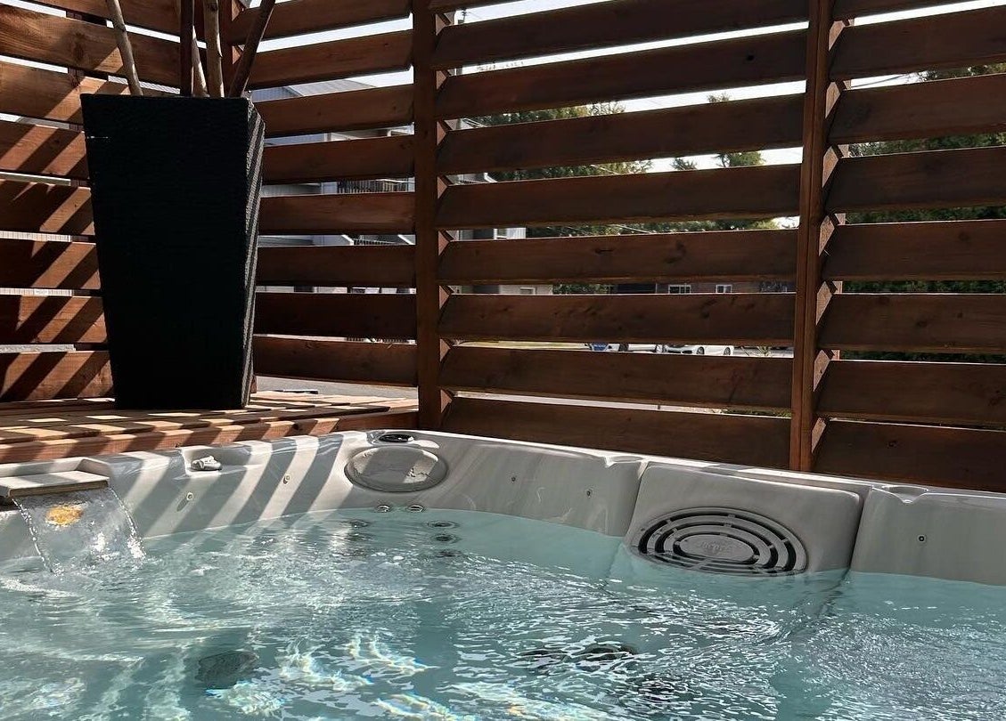 Jacuzzi extérieur à Spa Douce Heure, Les Coteaux, Québec, CA, entouré de cloisons en bois élégantes.