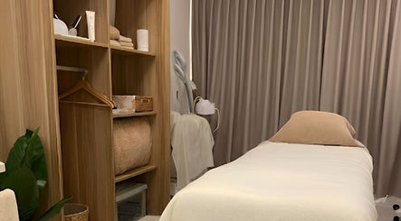 Cozy treatment room at Nadesico Beauty & Healing, Singapore, SG with soft linens and wooden decor.