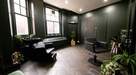 Elegant salon interior at Jivan Room, London, England, GB featuring modern black chairs and lush greenery.