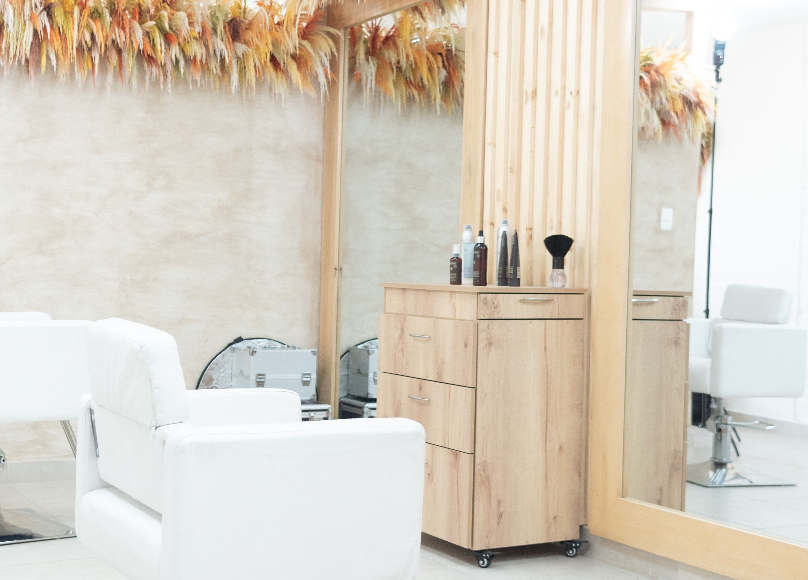 Interior moderno de OKO - Belleza con Propósito en Quito, Ecuador, con sillas y espejo estilístico.