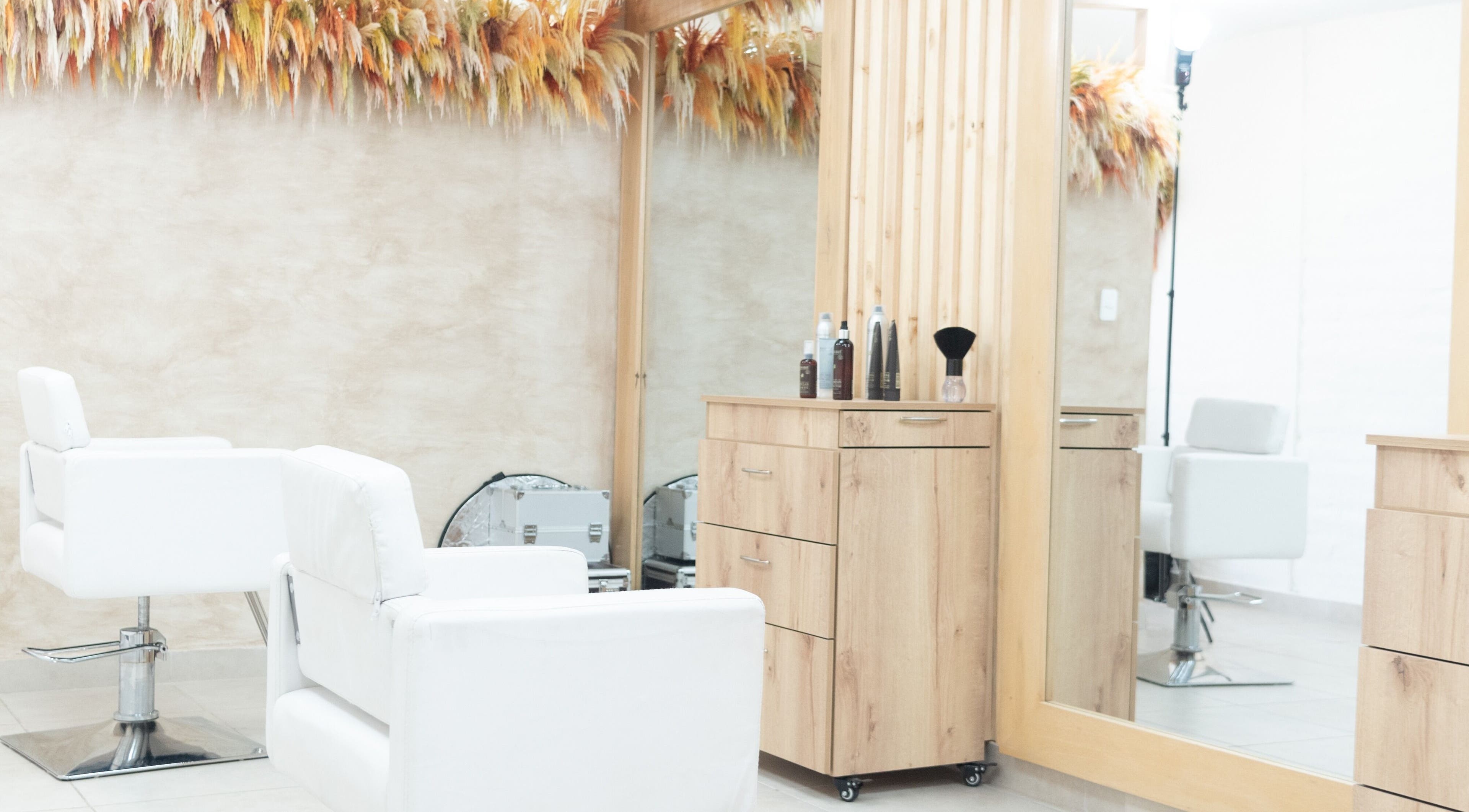 Interior moderno de OKO - Belleza con Propósito en Quito, Ecuador, con sillas y espejo estilístico.