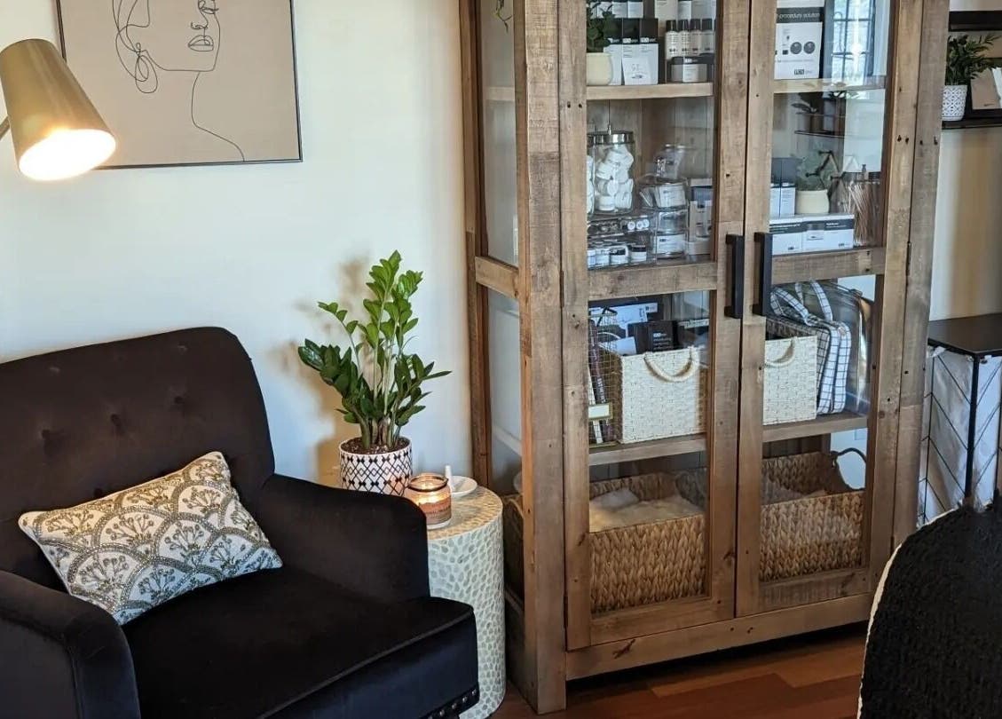 Inviting relaxation area at S.L. Skin Studio, Hampstead, New Hampshire featuring a comfy chair and chic cabinet.