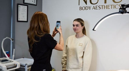 Consultation at NUYU Body Aesthetics in Beckenham, England with a professional capturing patient details.