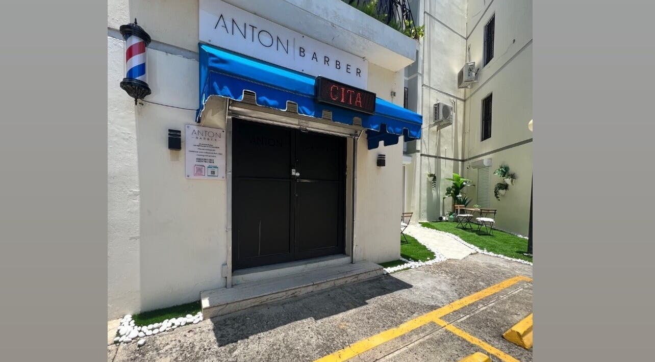 Entrada principal de Anton Barber en Santo Domingo, Distrito Nacional, DO, con toldo azul y señal de cita.