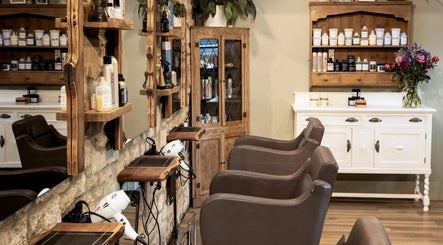Elegant salon interior at The Hair Loft, Stoke-sub-Hamdon, England, GB, showcasing wooden shelves and styling chairs.