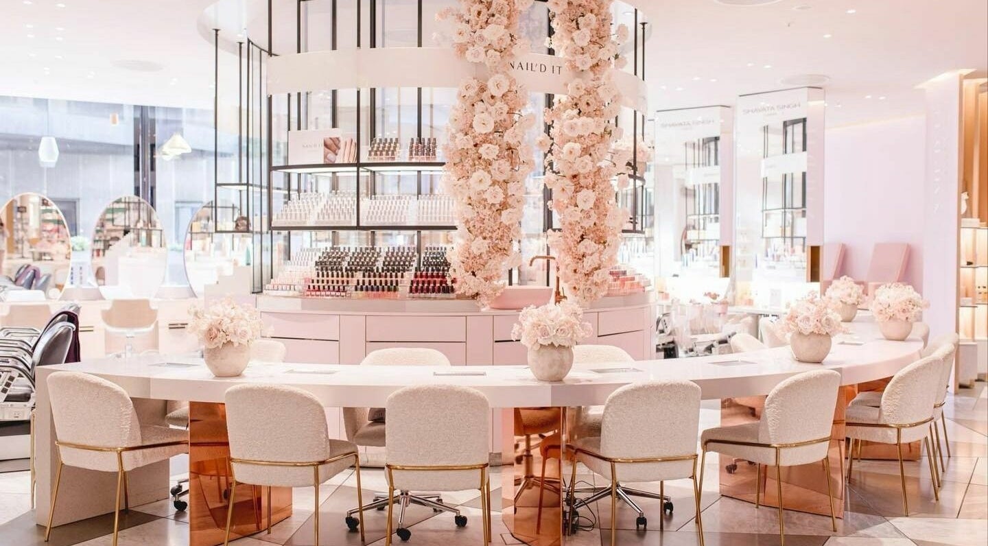 Elegant interior of Nail'd It Battersea in London, England, GB, showcasing chic nail stations and floral decor.