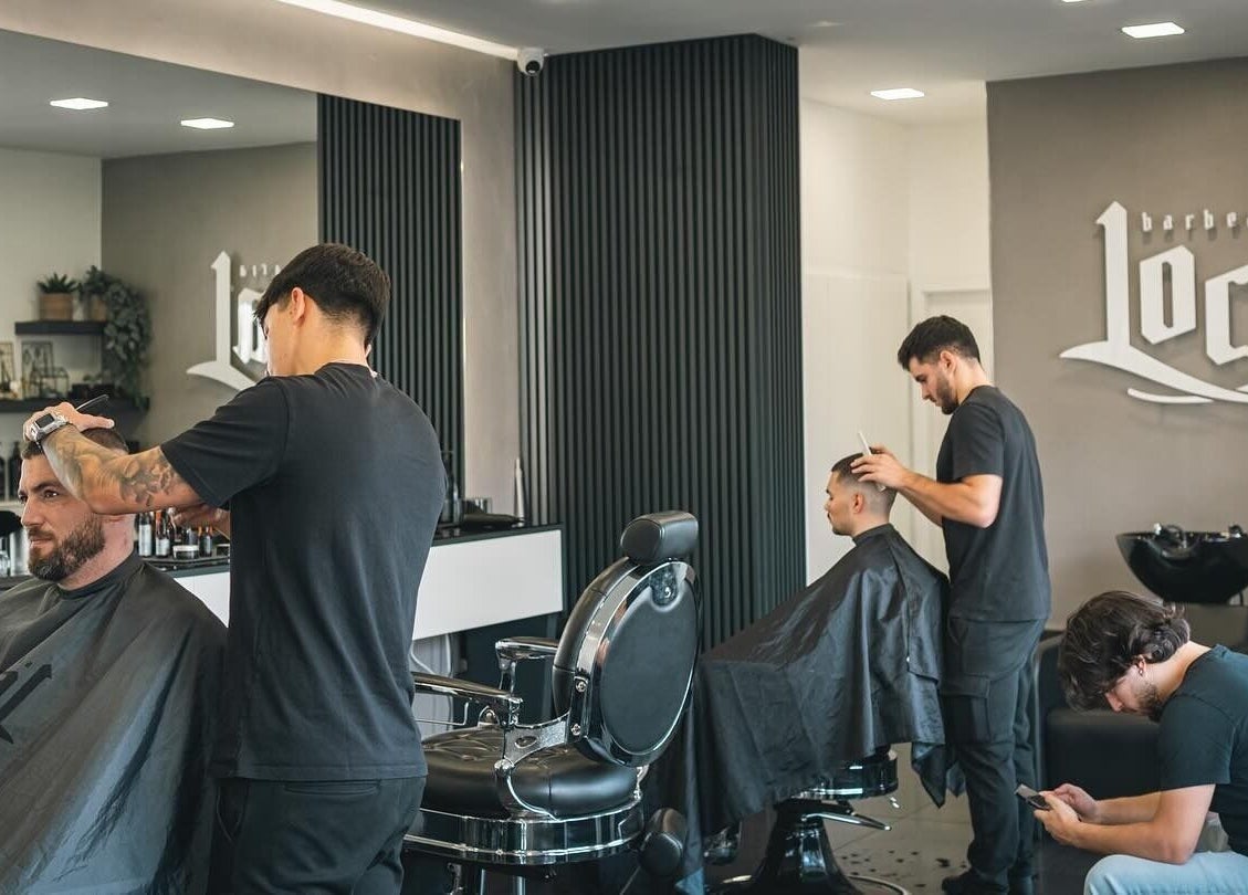 Interior da Barbearia Local - Areal de Cima em Braga, Portugal, com clientes em corte de cabelo.