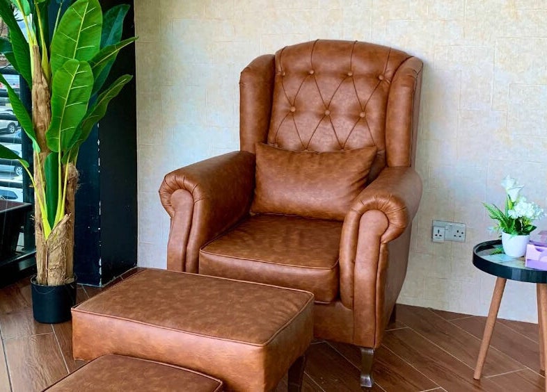Cozy leather armchair at Verve Men's Salon & Spa, الشارقة, إمارة الشارقةّ, AE, corner view with plant.