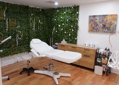 Relaxing treatment room at All That Beauty Bar, Ottawa, Ontario, CA, featuring a lush green wall and comfy chair.