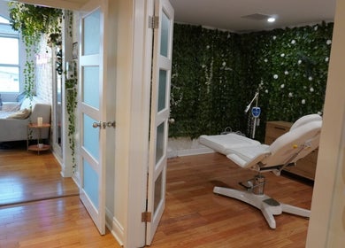 Spa room with white chair and lush greenery at All That Beauty Bar, Ottawa, Ontario, CA.