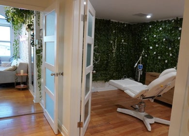 Spa room at All That Beauty Bar, Ottawa, Ontario, CA, featuring lush greenery and a cozy treatment chair.