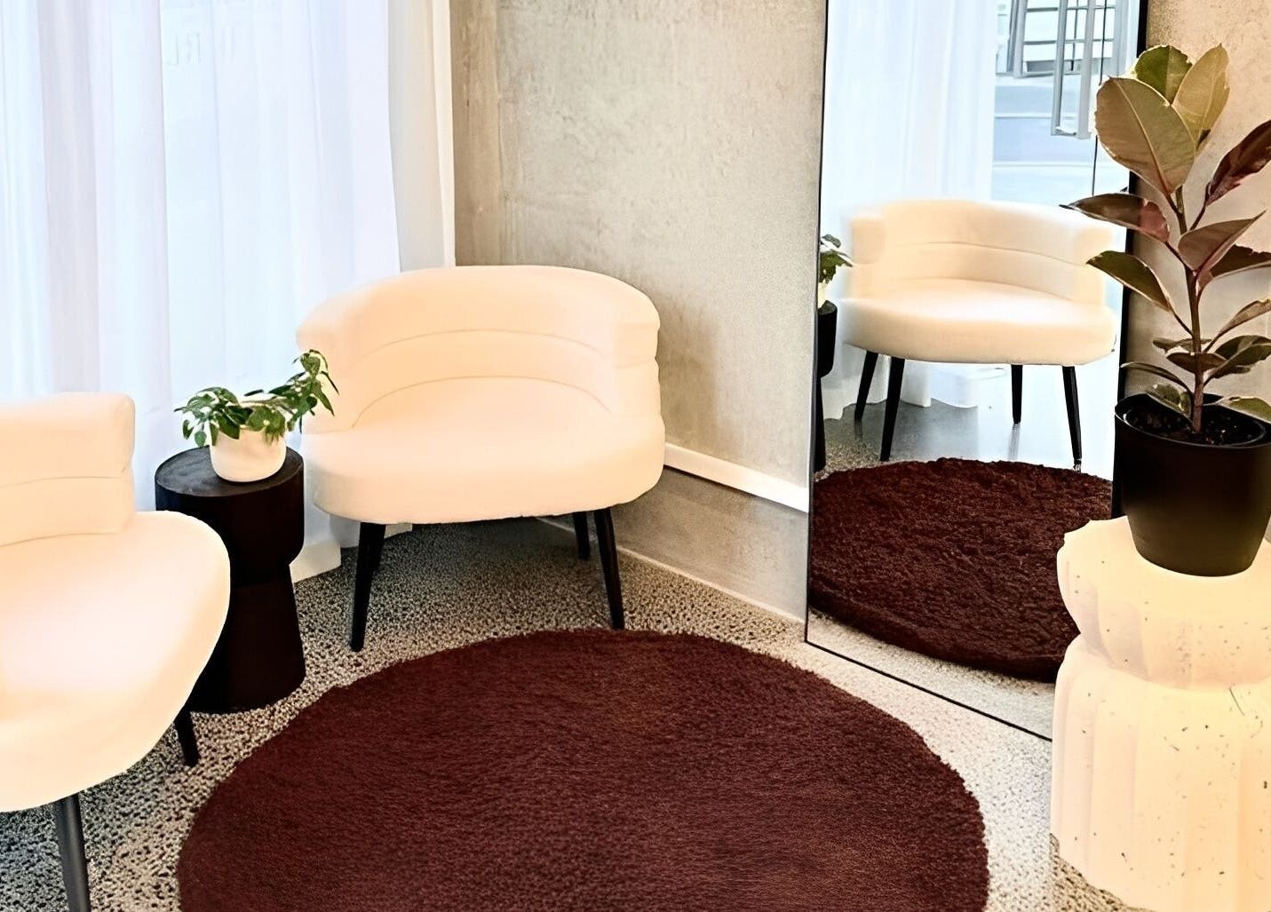 Elegant lounge area at Studio Ten, Auckland, NZ featuring white chairs, plants, and a mirror.