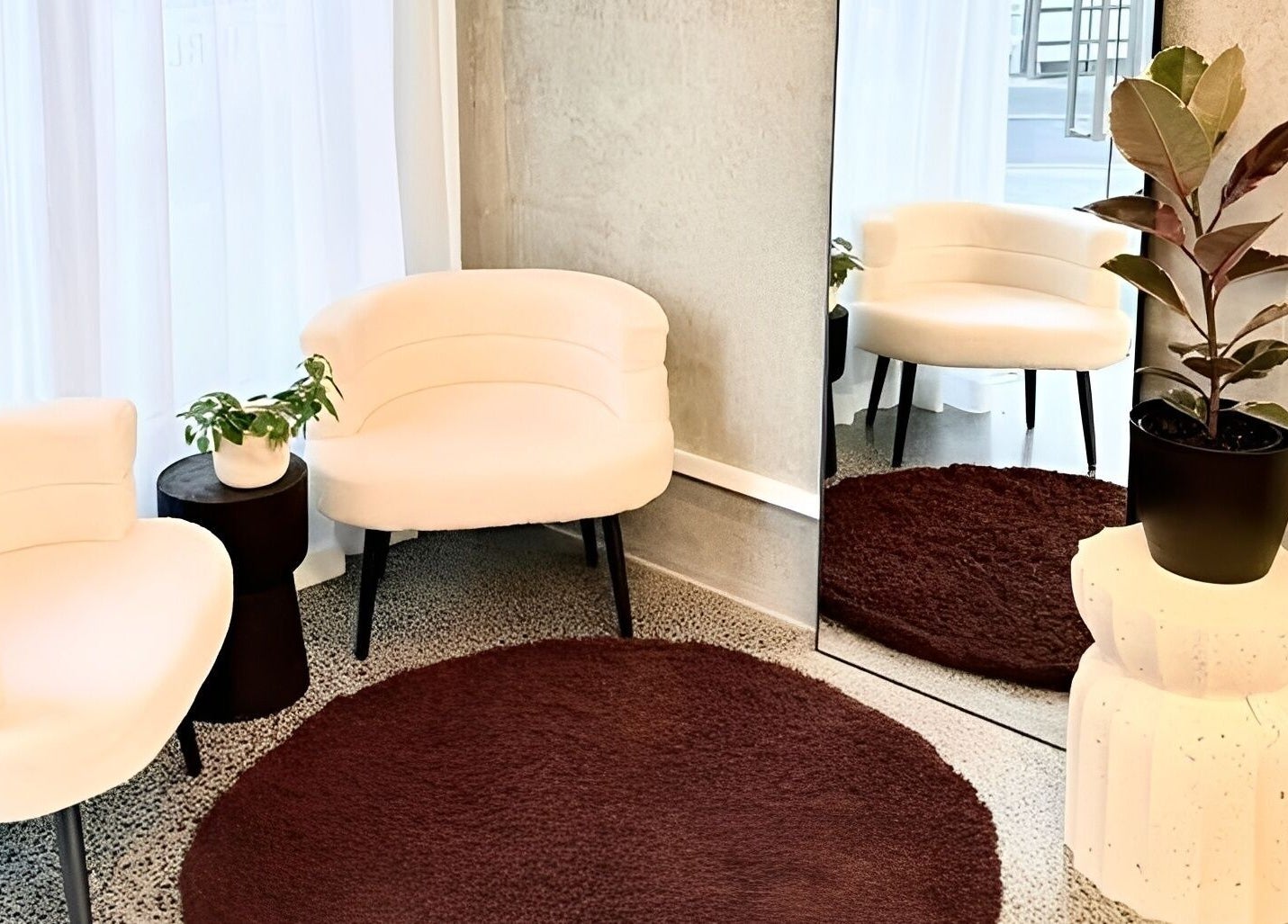 Elegant lounge area at Studio Ten, Auckland, NZ featuring white chairs, plants, and a mirror.