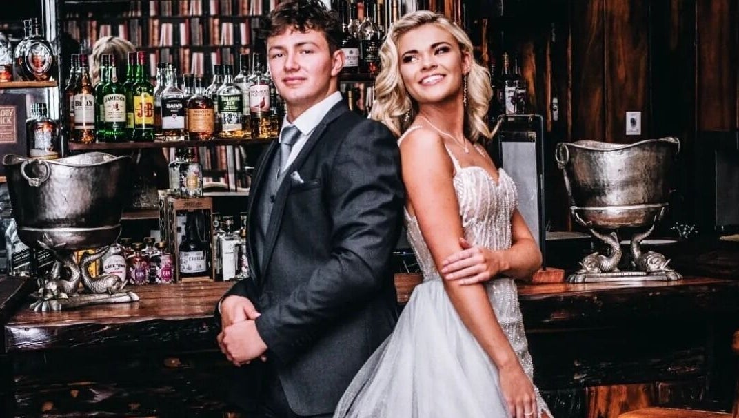 Couple in formal attire at Go and Glow Studio, Centurion, Gauteng, ZA, with bar backdrop.