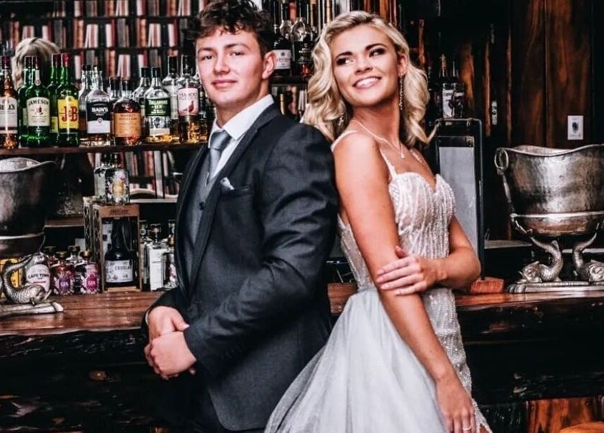 Couple in formal attire at Go and Glow Studio, Centurion, Gauteng, ZA, with bar backdrop.