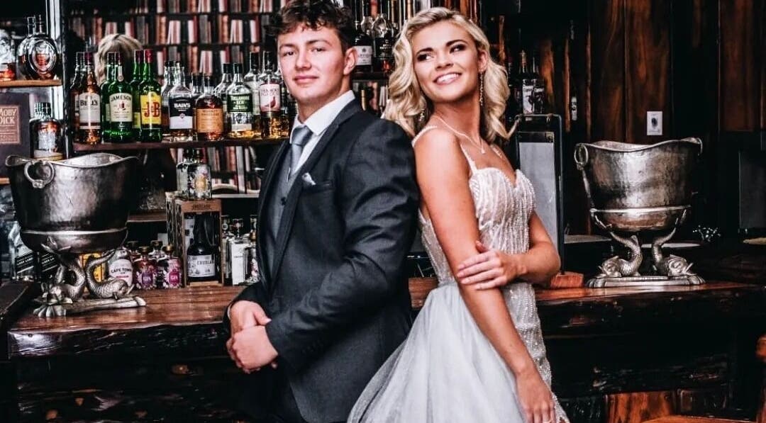 Couple in formal attire at Go and Glow Studio, Centurion, Gauteng, ZA, with bar backdrop.