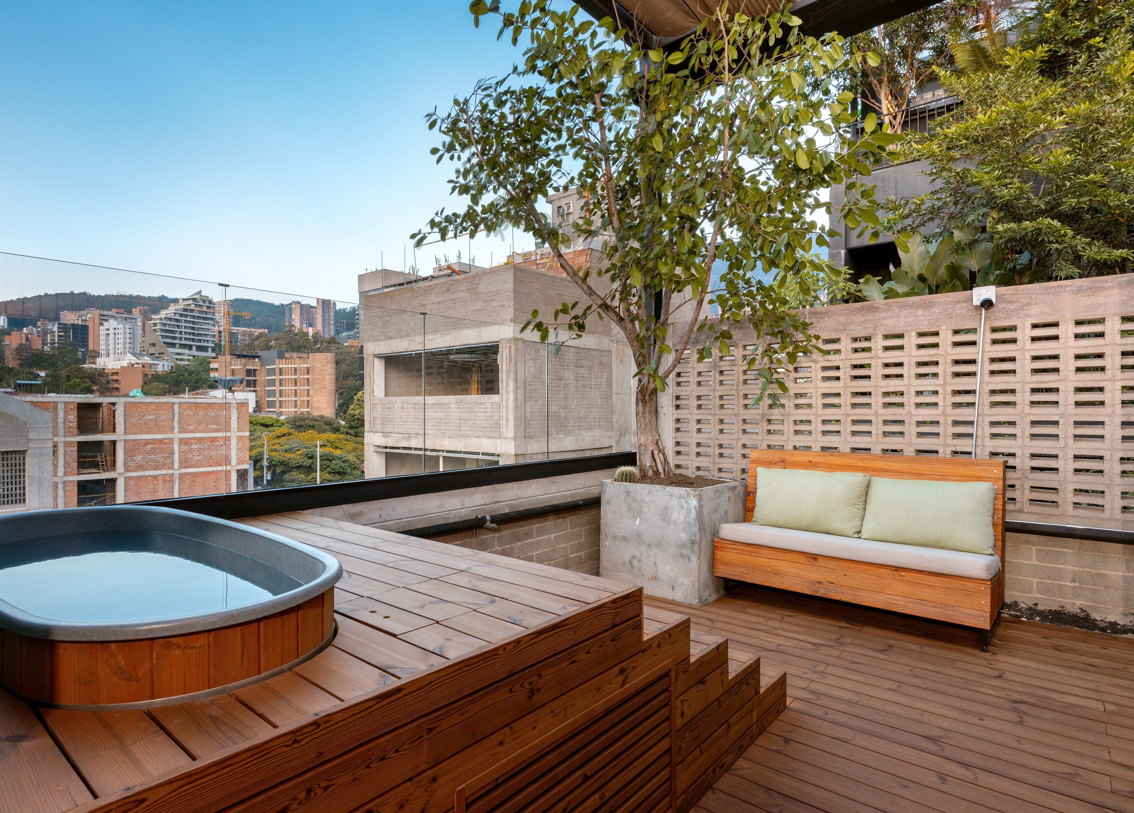 Relaxing outdoor deck at Celestino Spa, Medellín, Antioquia, CO with a wooden hot tub and city view.