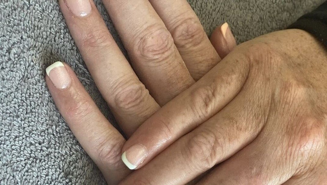 Beautiful French manicure at Ego Nails & Beauty in Workington, England, GB showcased on a hand resting on a towel.
