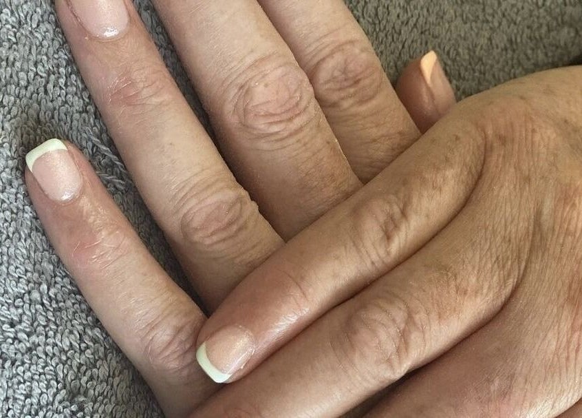 Beautiful French manicure at Ego Nails & Beauty in Workington, England, GB showcased on a hand resting on a towel.
