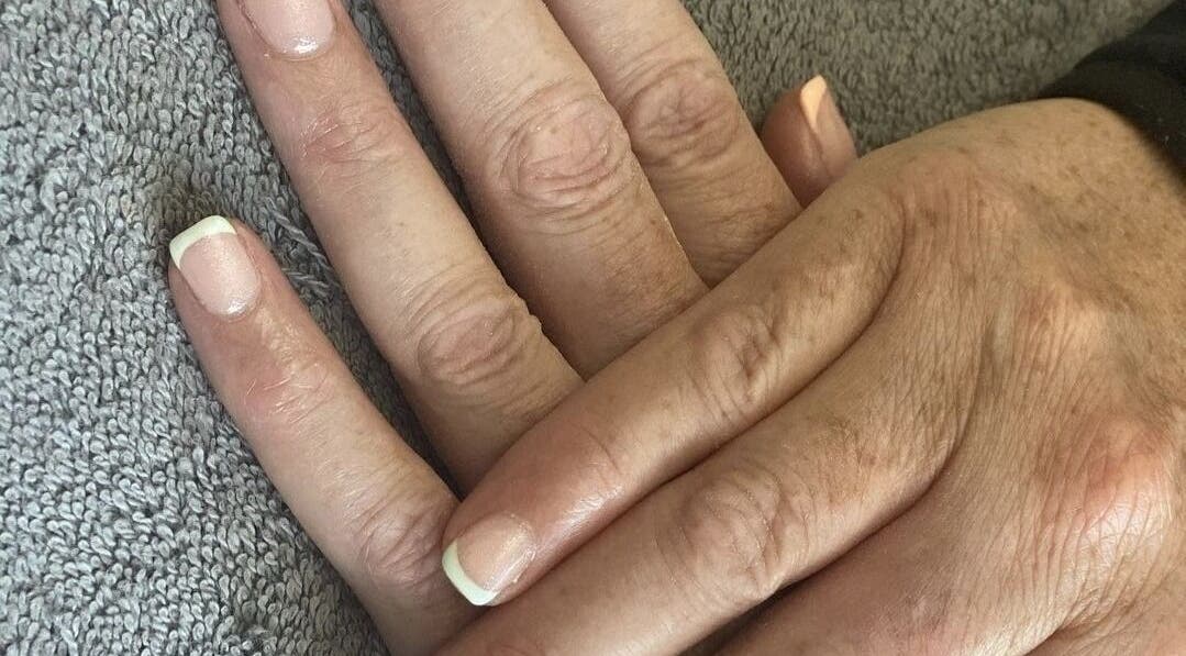 Beautiful French manicure at Ego Nails & Beauty in Workington, England, GB showcased on a hand resting on a towel.