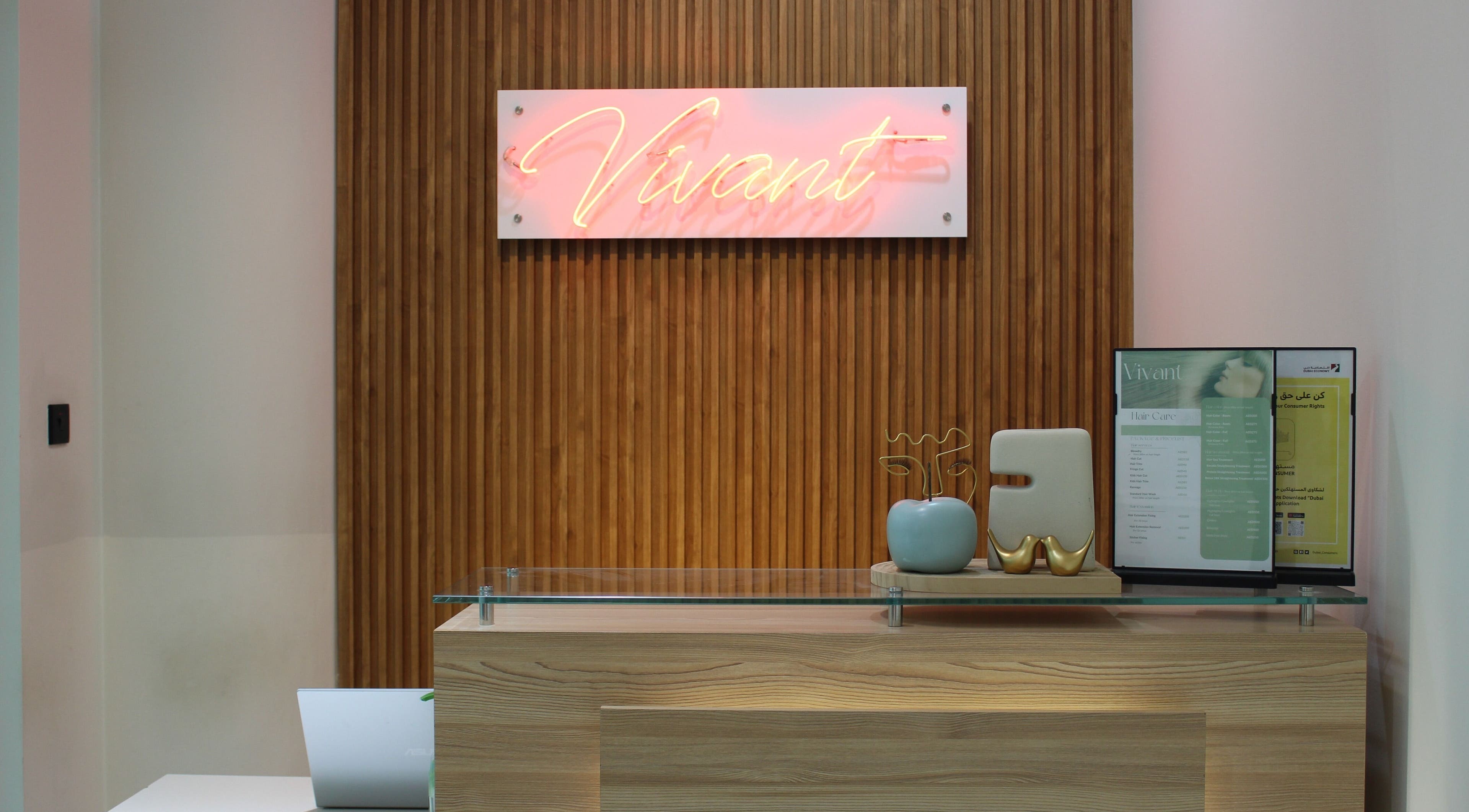 Reception area at Vivant Beauty Salon, Dubai, Dubai, AE with a neon sign and modern decor.