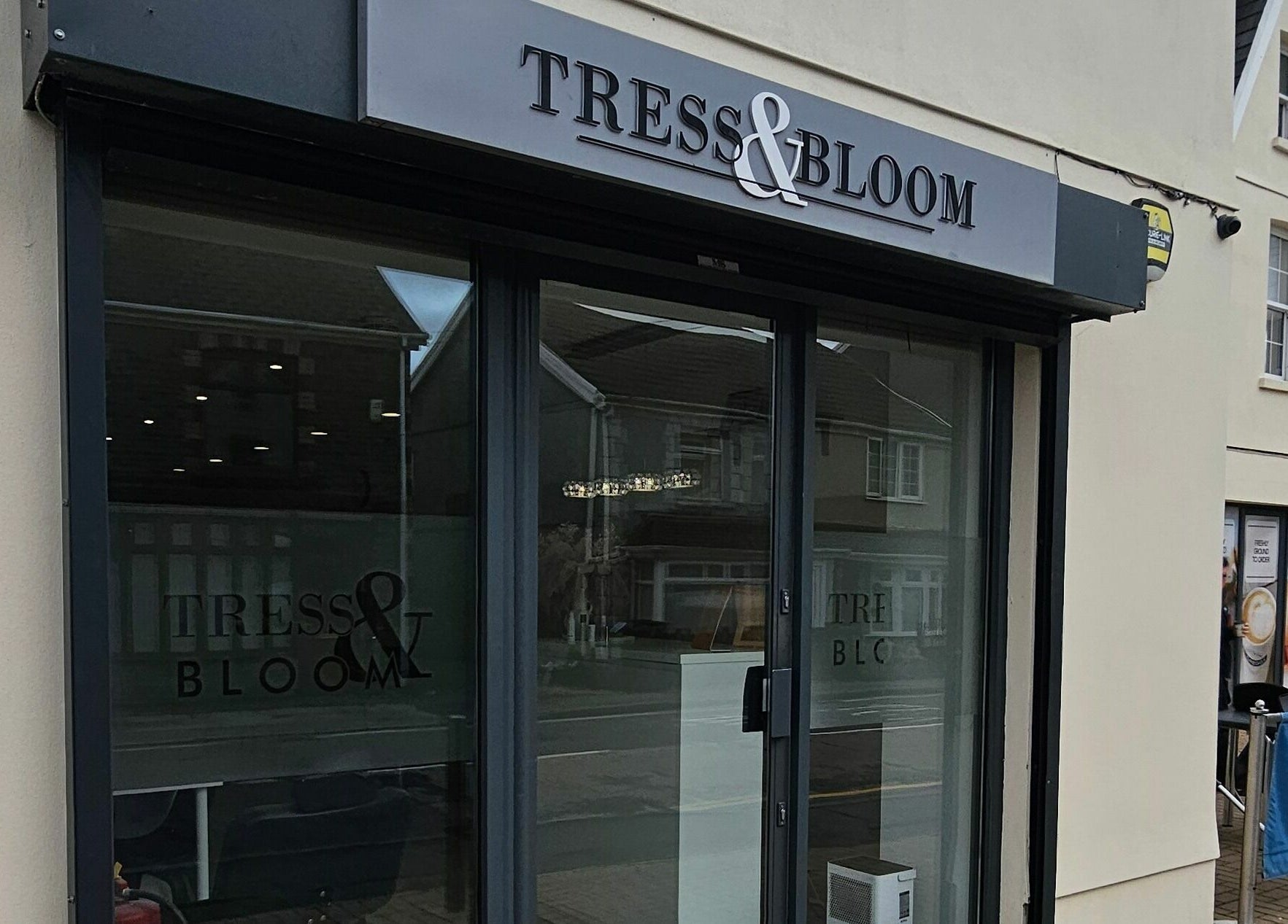 Exterior of Tress and Bloom Neath salon in Neath, Wales, GB showcasing elegant glass doors.