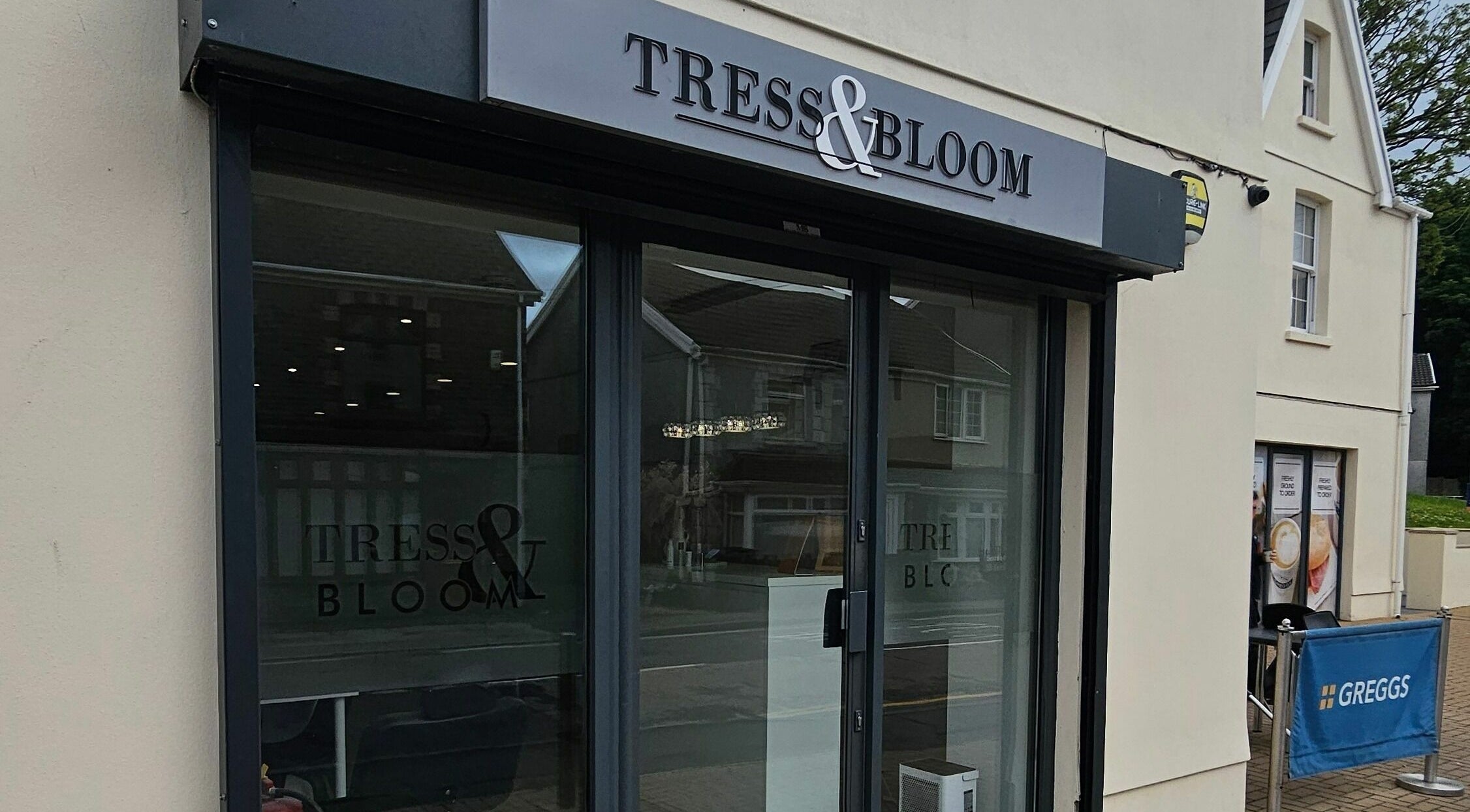 Exterior of Tress and Bloom Neath salon in Neath, Wales, GB showcasing elegant glass doors.