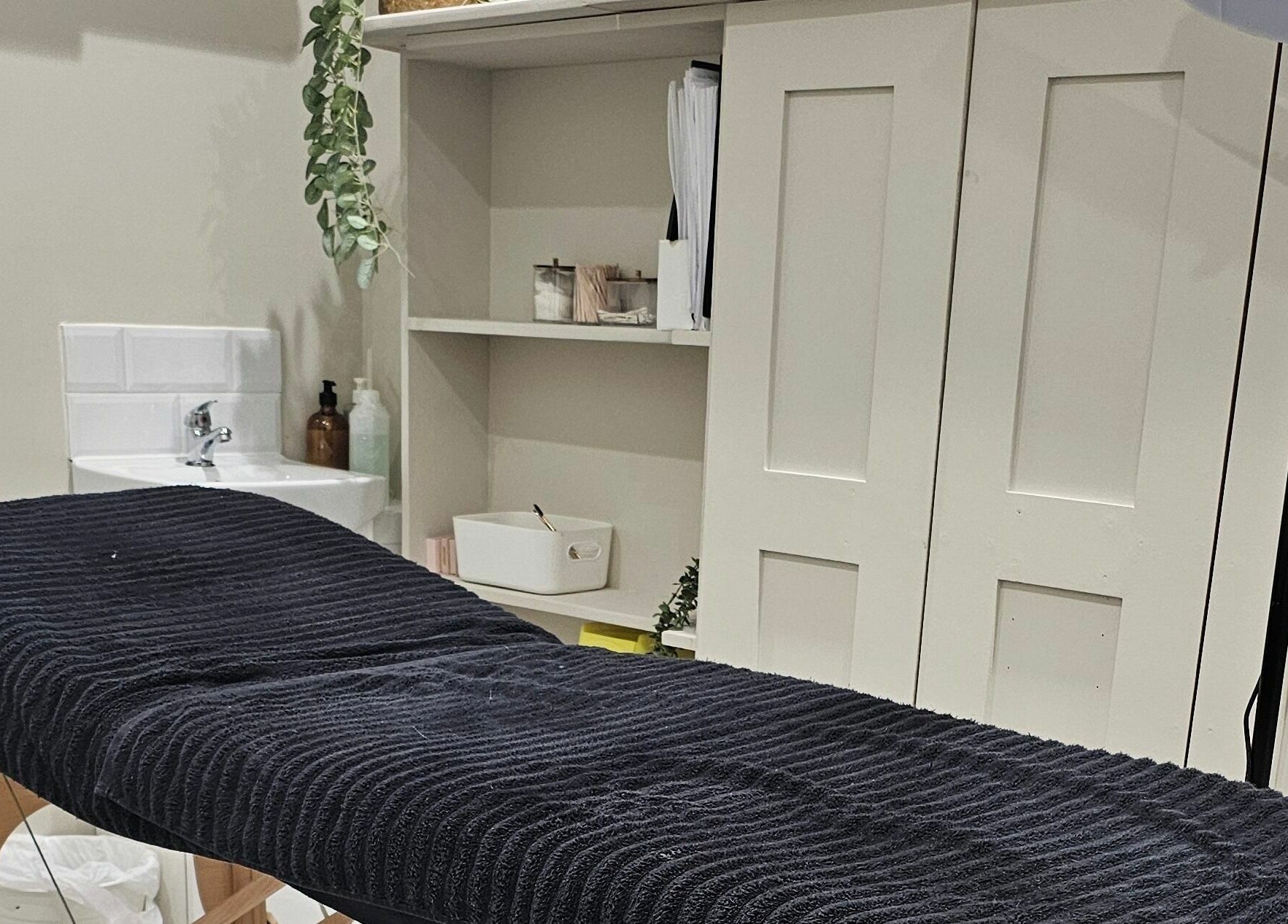 Cozy treatment room at Tress and Bloom Neath, Neath, Wales, GB featuring a massage table and minimalist decor.