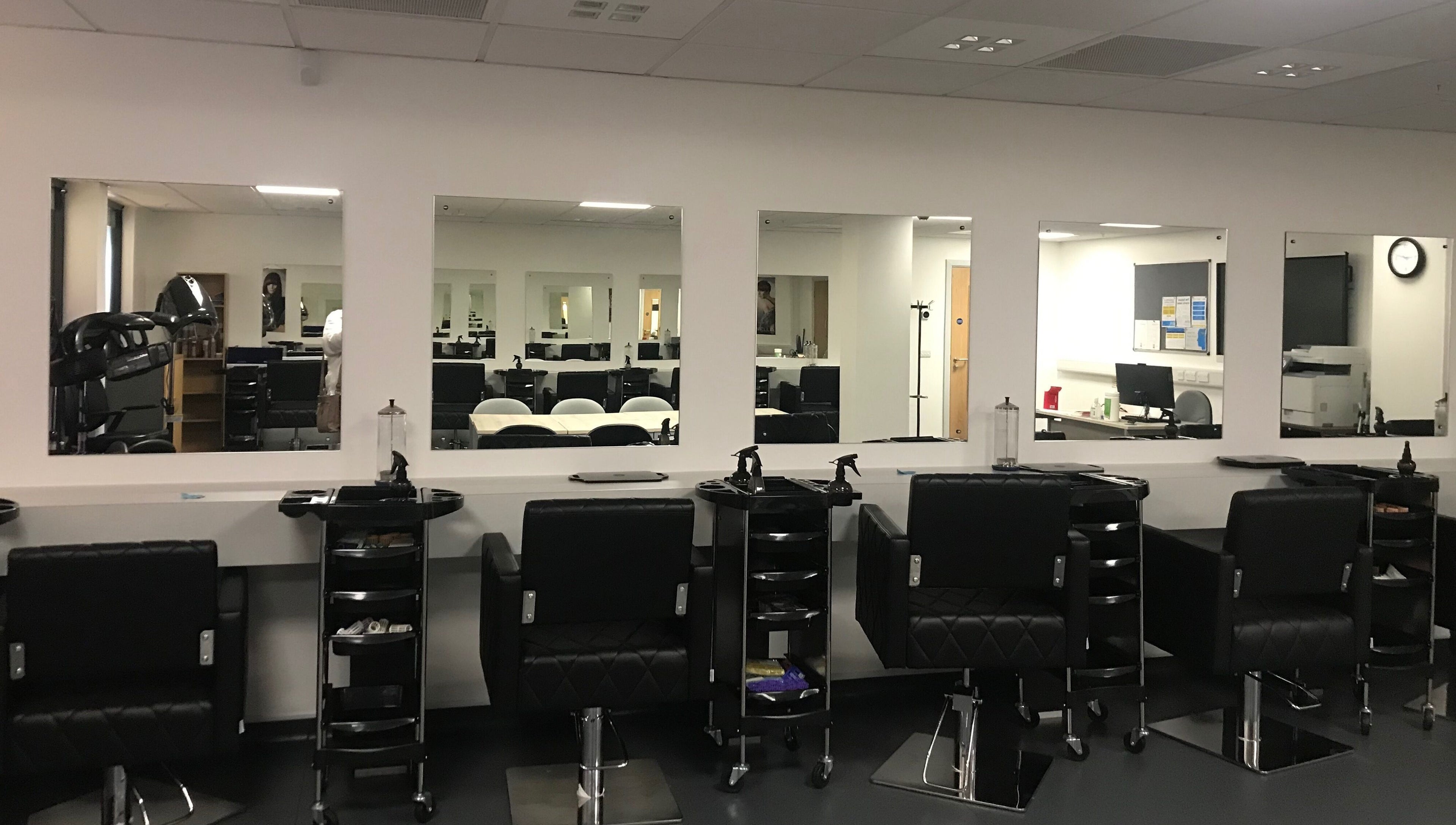 Modern setup at Skills and Learning Barbering Training Salon in Poole, England, GB featuring sleek styling chairs.