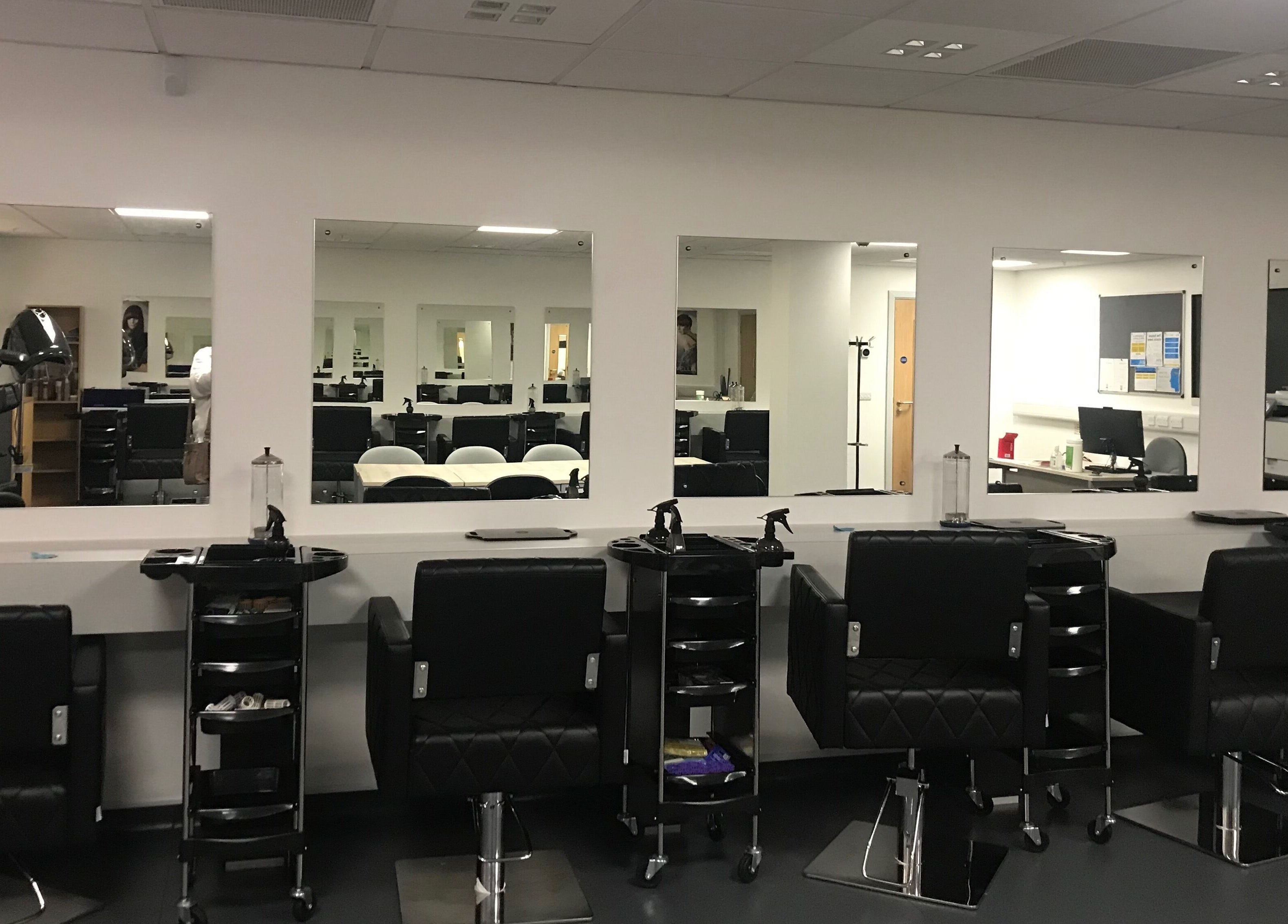Modern setup at Skills and Learning Barbering Training Salon in Poole, England, GB featuring sleek styling chairs.