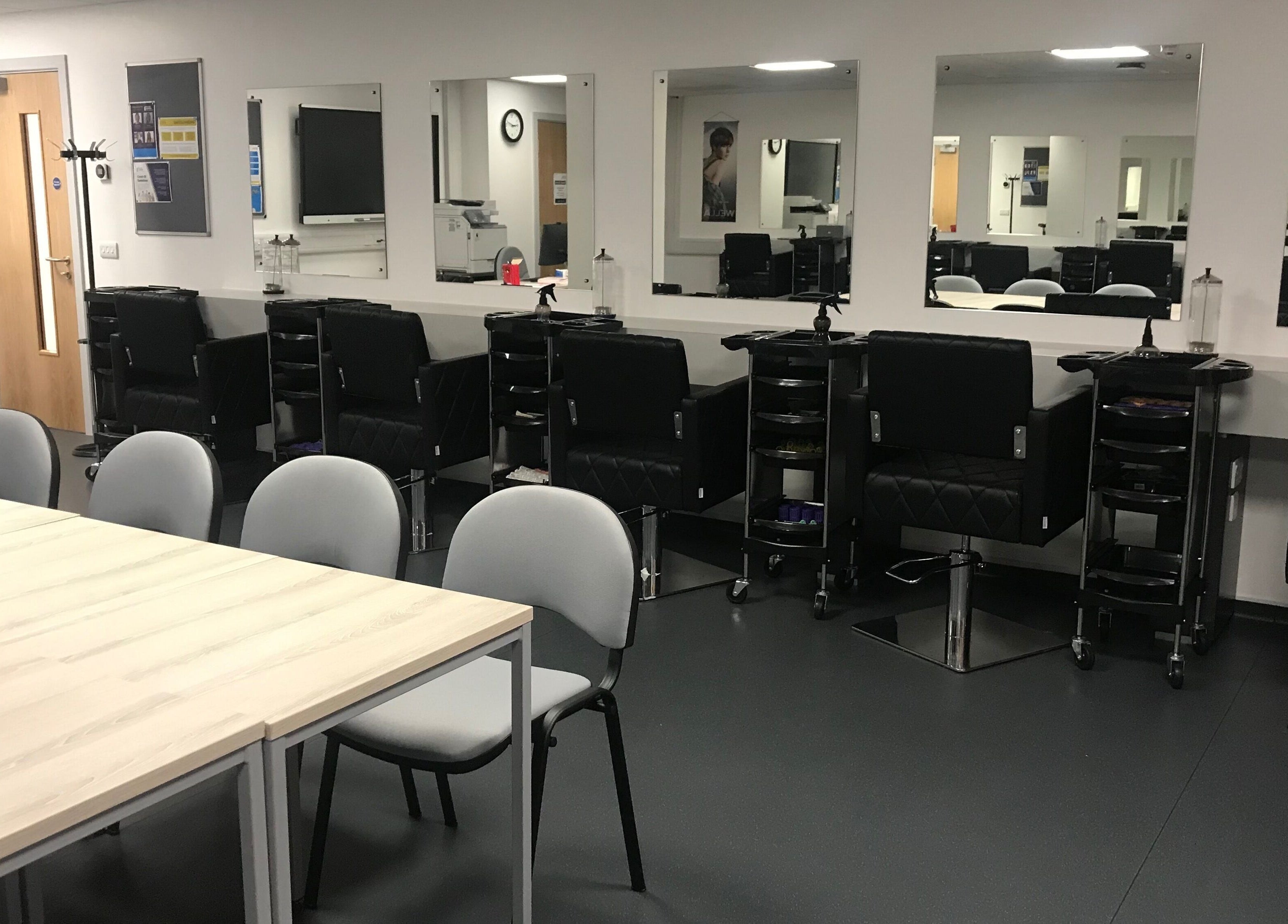 Interior of Skills and Learning Barbering Training Salon in Poole, England, showcasing sleek styling chairs.