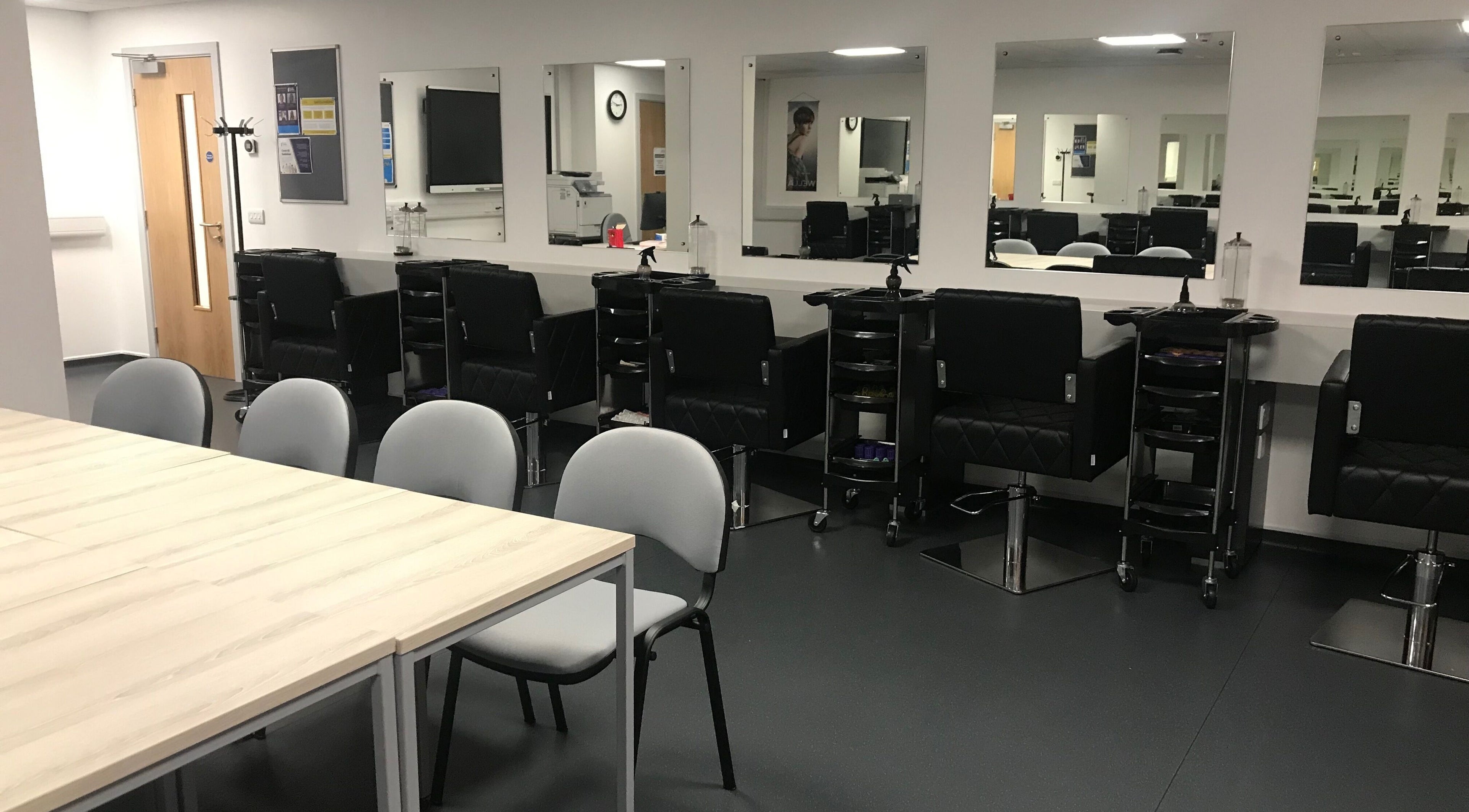 Interior of Skills and Learning Barbering Training Salon in Poole, England, showcasing sleek styling chairs.