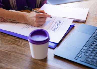 Workspace at Fempire Beauty, Glasgow, Scotland with documents, laptop, and a coffee cup.