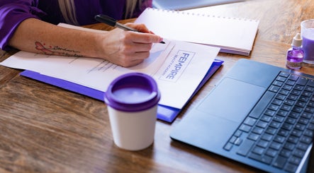 Workspace at Fempire Beauty, Glasgow, Scotland with documents, laptop, and a coffee cup.