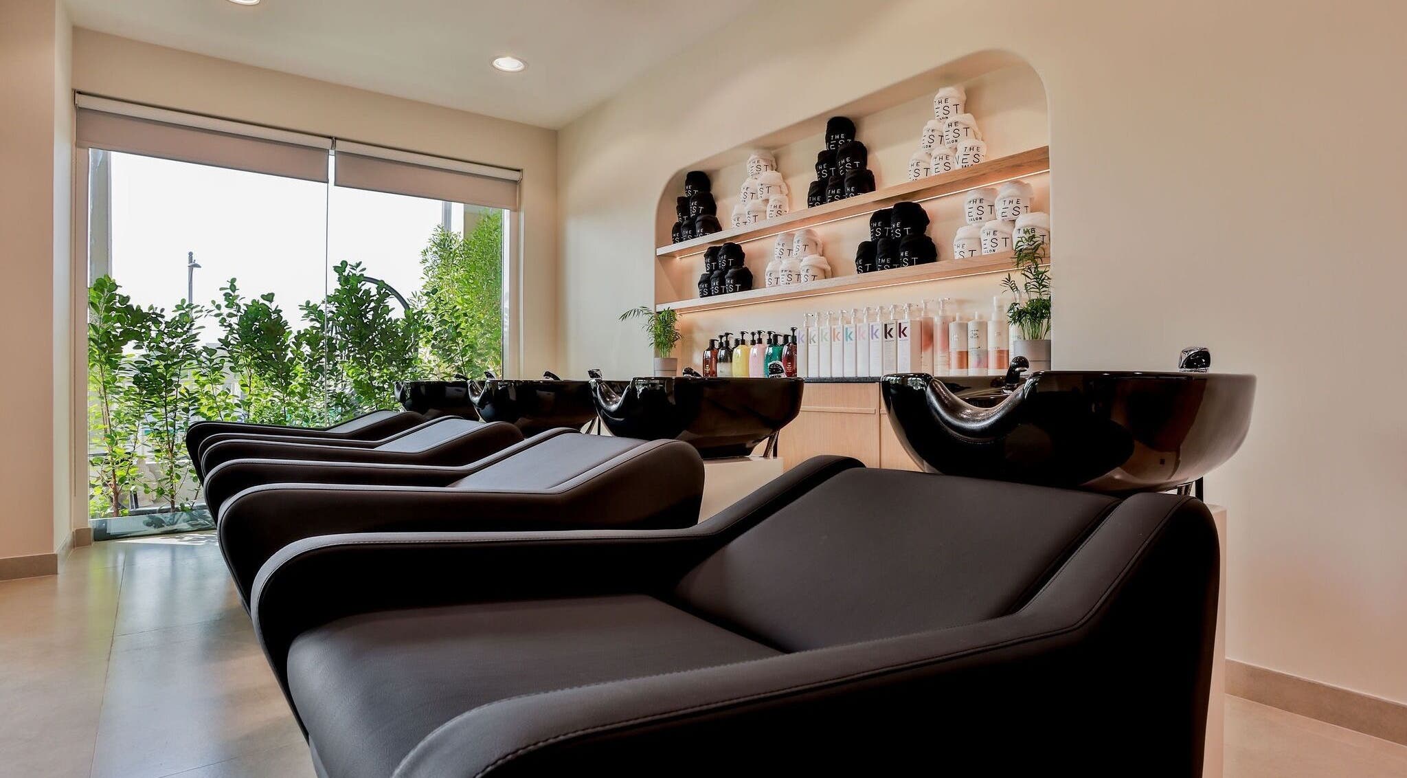 Elegant hair wash station at The Nest Hair Salon, Jumeirah, Dubai, AE with modern black chairs.