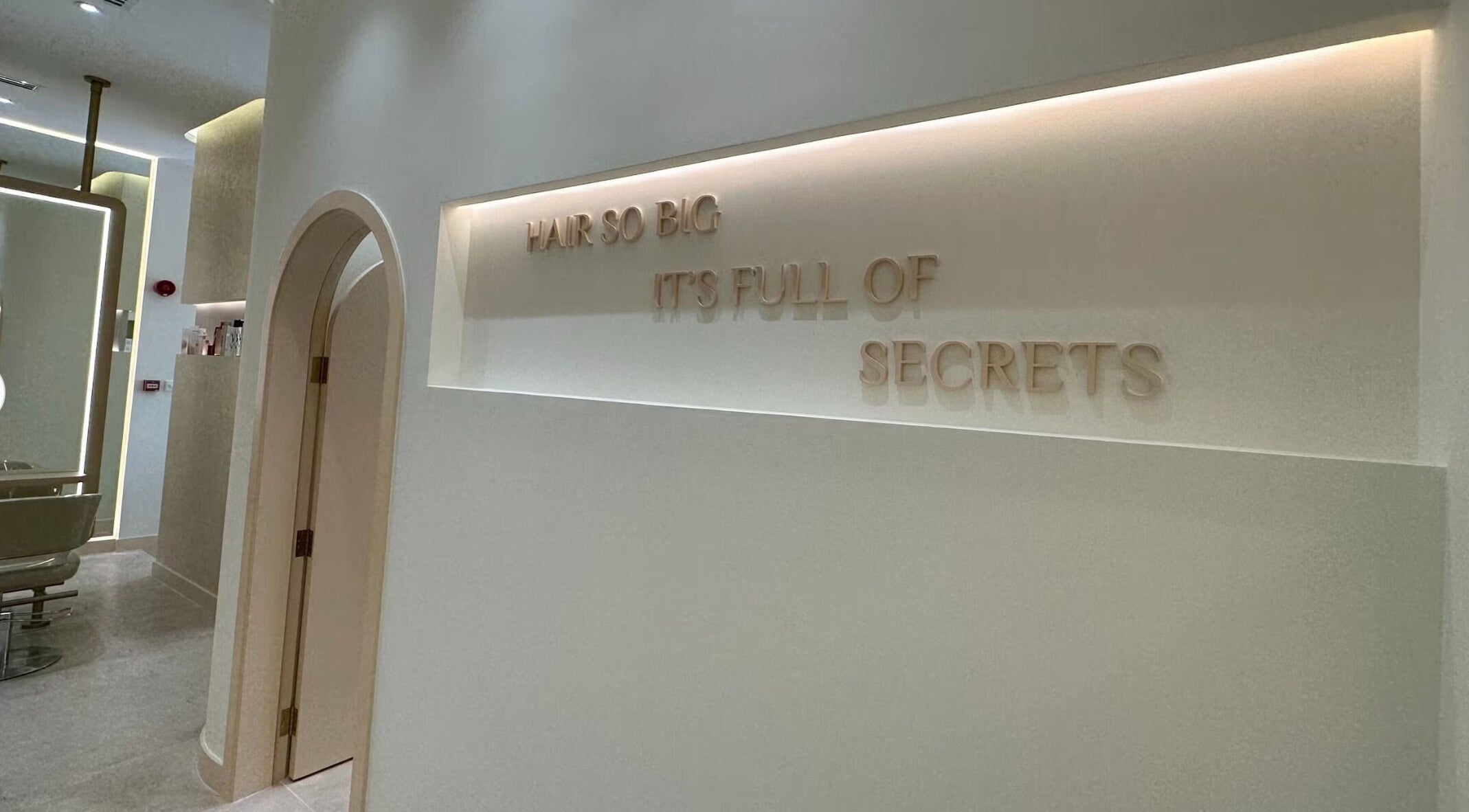 Stylish interior with arched door at The Nest Salon, Sobha Hartland, دبي, Dubai, AE. Wall text says 'Hair so big'.