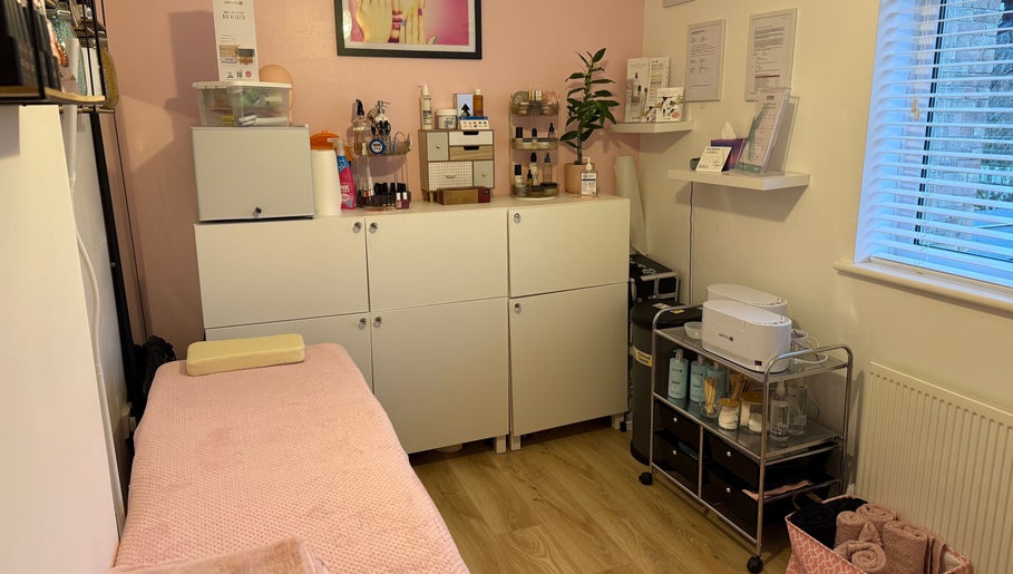 Orchid Beauty treatment room in Crawley, England, GB with a cozy pink massage table and organized beauty products.