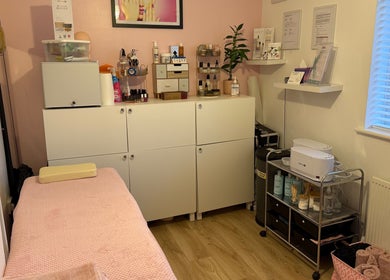 Orchid Beauty treatment room in Crawley, England, GB with a cozy pink massage table and organized beauty products.