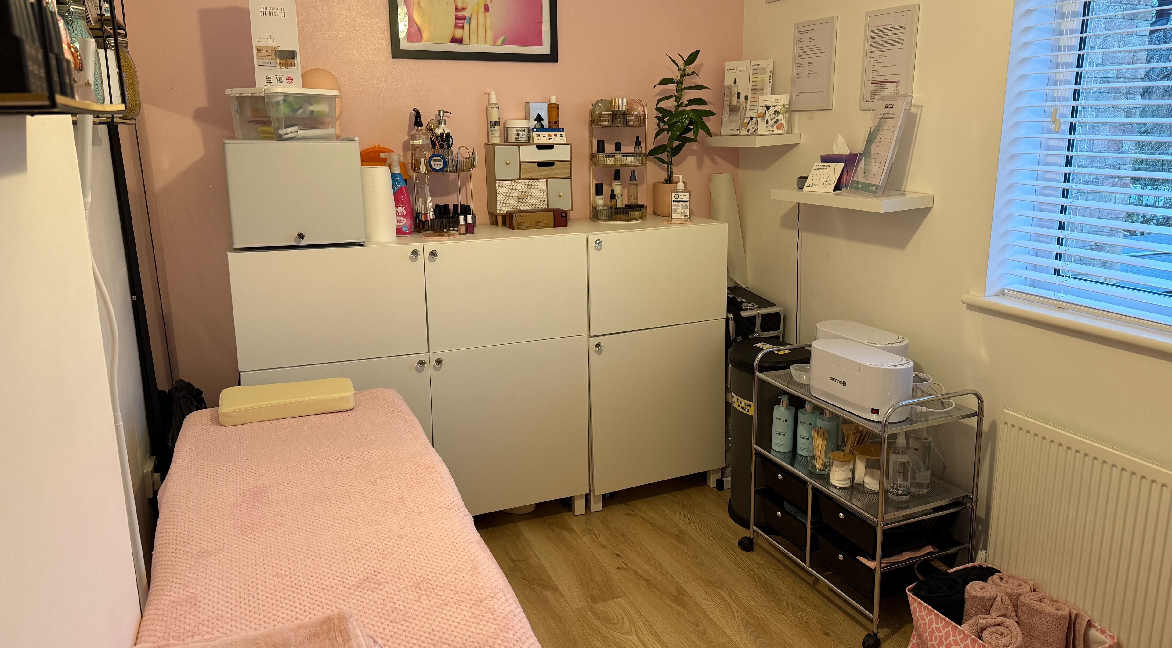 Orchid Beauty treatment room in Crawley, England, GB with a cozy pink massage table and organized beauty products.