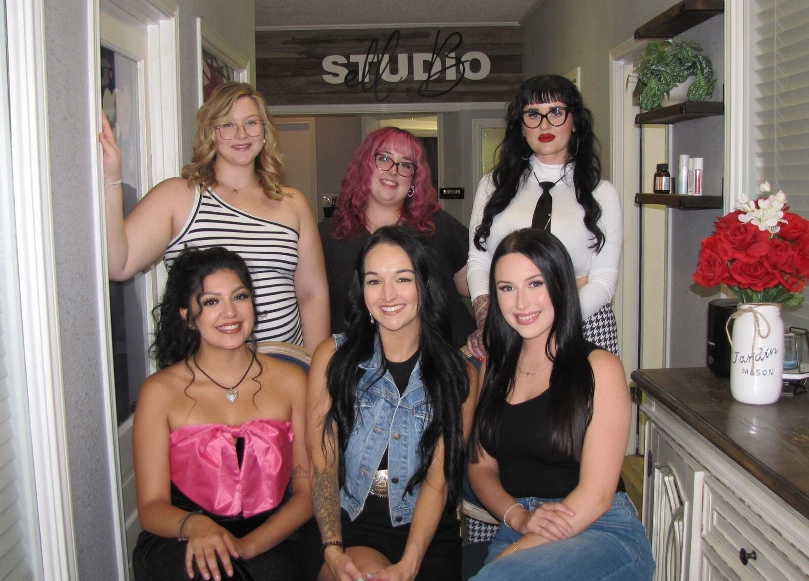 Staff at Studio ELL.B in Texarkana, Texas, US, posed in a stylish interior with a floral decor backdrop.