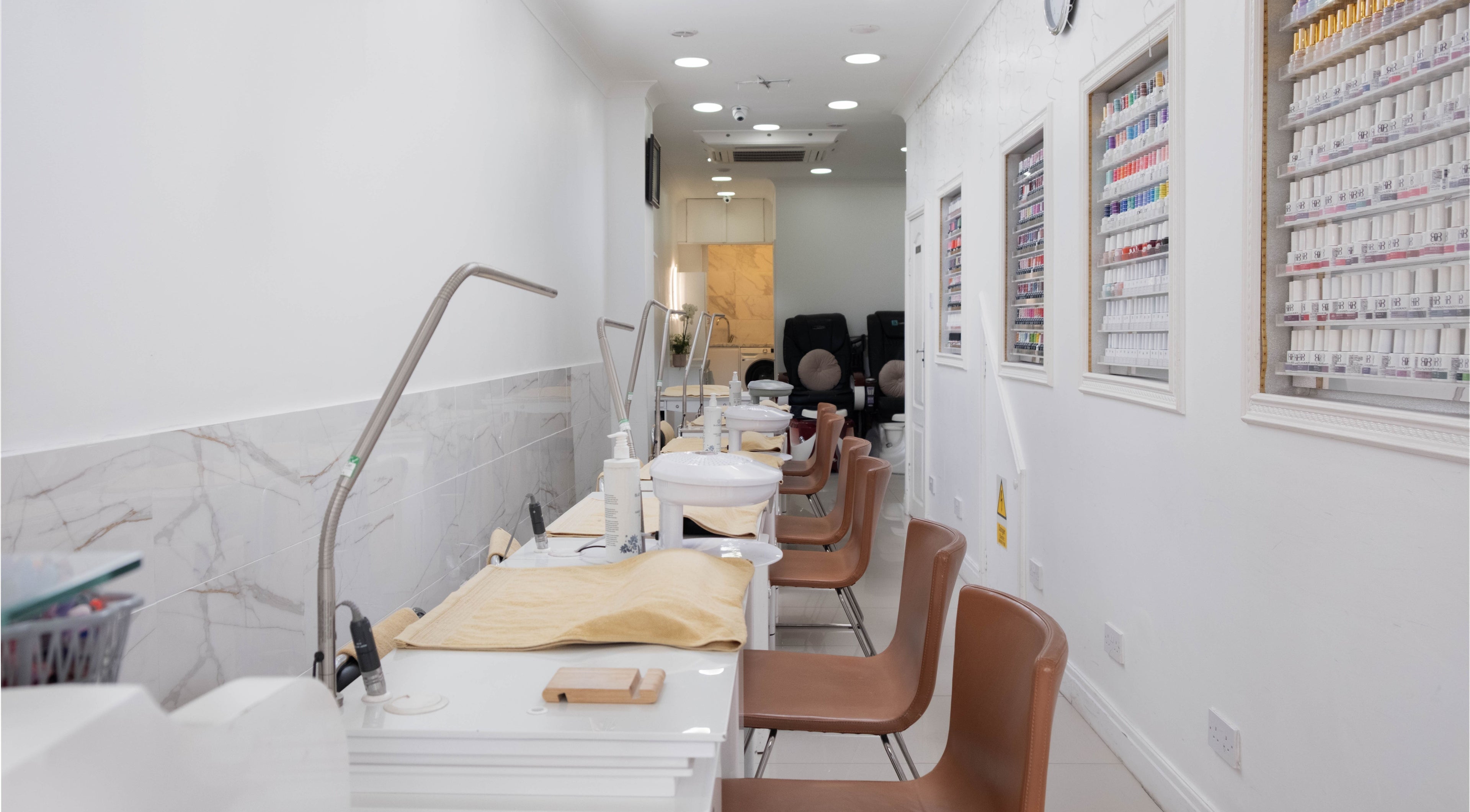 Interior view of Brick Lane Nail Spa in London, England, GB, showcasing manicure stations and gel colors.