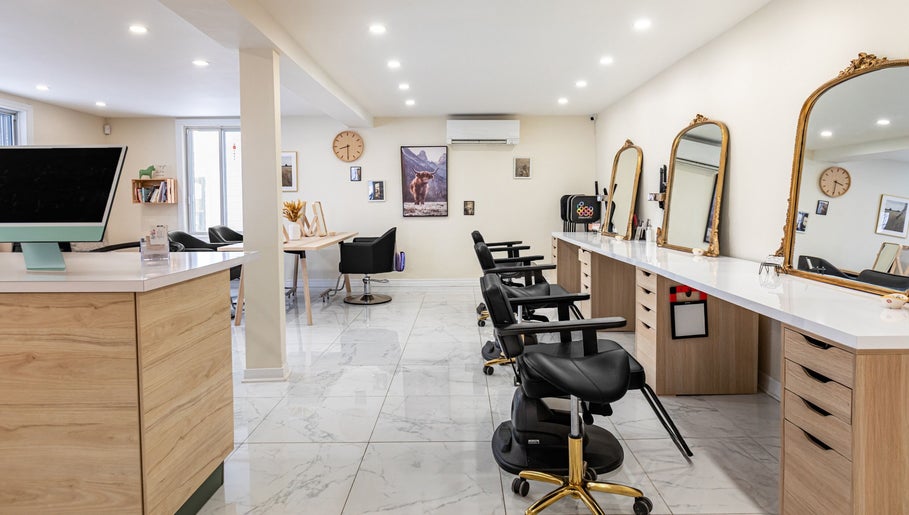 Intérieur élégant de Le Préau Coiffure - Esthétique à Laval, Québec, CA, avec miroirs dorés et chaises modernes.