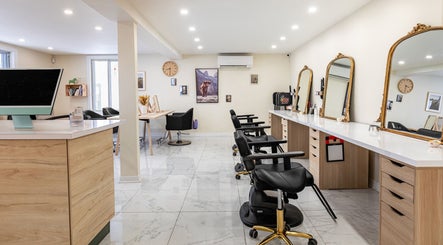 Intérieur élégant de Le Préau Coiffure - Esthétique à Laval, Québec, CA, avec miroirs dorés et chaises modernes.