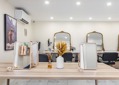 Intérieur élégant de Le Préau Coiffure - Esthétique à Laval, Québec, CA avec miroirs dorés et déco moderne.