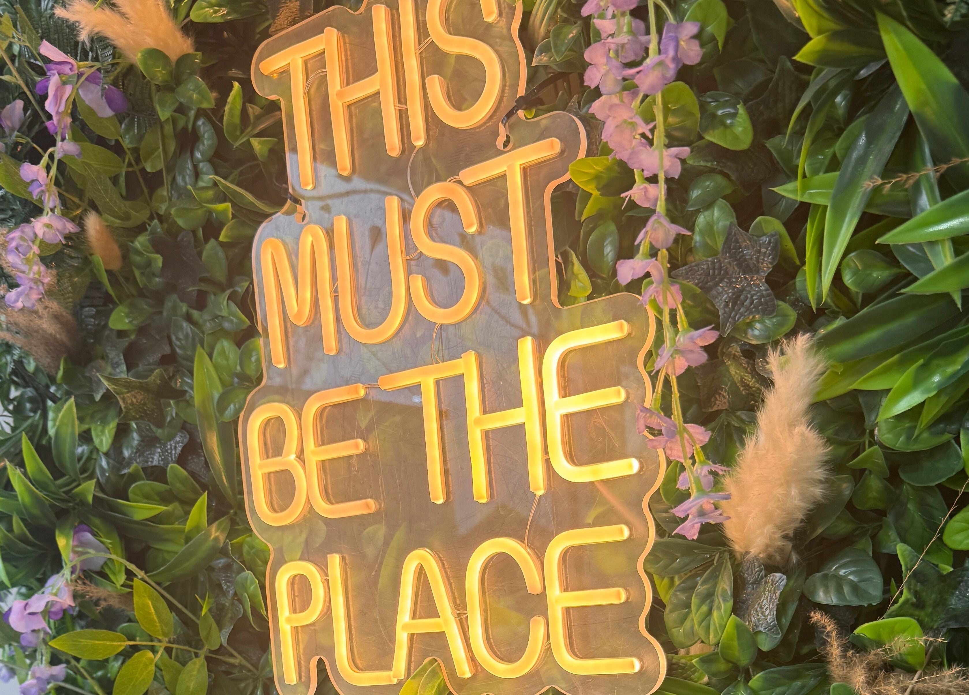 Vibrant neon sign amidst lush greenery at Sie Skin Spa, Stalybridge, England, GB.