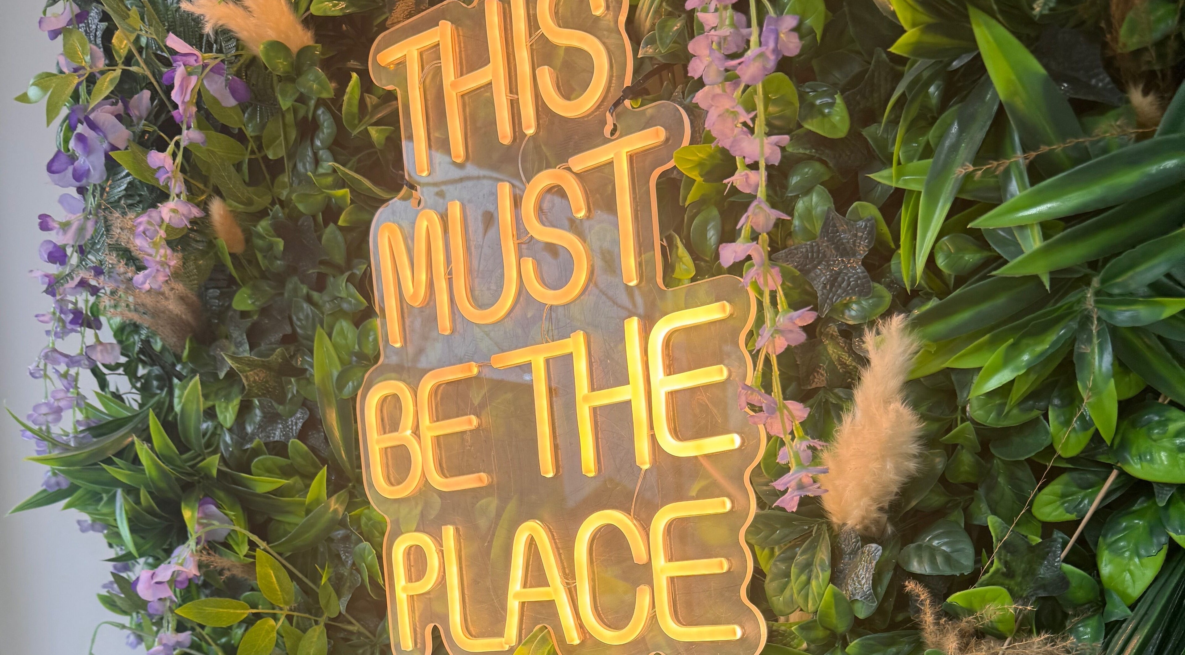 Vibrant neon sign amidst lush greenery at Sie Skin Spa, Stalybridge, England, GB.