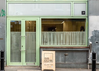 Front entrance of Haco 箱 Hair + Nails Hoxton, London, England, GB with mint green door and signage.