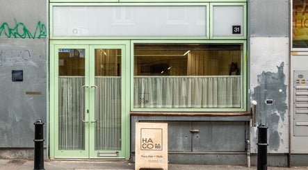 Front entrance of Haco 箱 Hair + Nails Hoxton, London, England, GB with mint green door and signage.