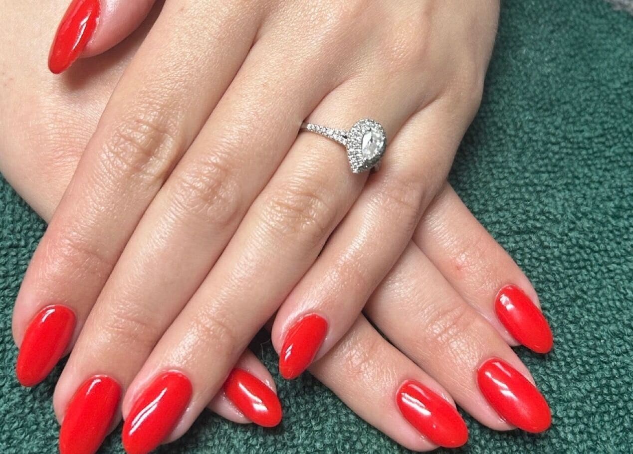 Close-up of vibrant red manicure with ring at ALM Beauty, Brighton And Hove, England, GB.